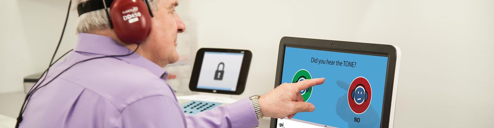 A patient taking an evaluation from AMTAS Pro automated audiometry in a sound booth